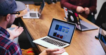A team discusses TikTok content strategy, with laptops showing digital dashboards in a collaborative setting.