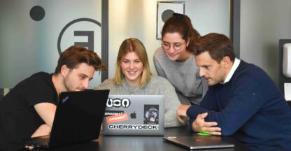 A group brainstorms TikTok content strategy, collaborating on laptops in a modern office setting.